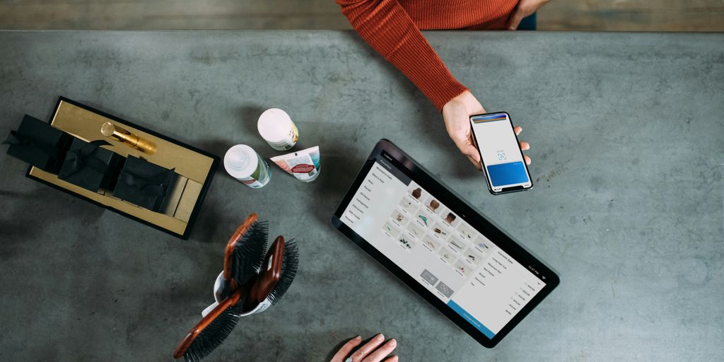 person holding smartphone beside tablet computer